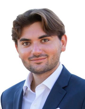 A man in a suit smiling against a white background.