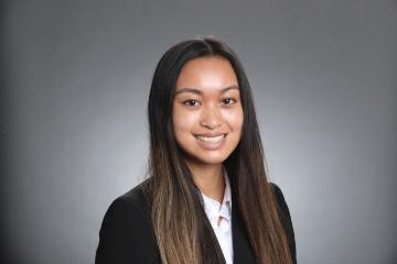 A person wearing a black blazer and white shirt smiling.
