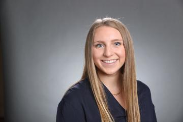 A person smiling against a gray background.