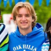 Four people by a pool with towels, wearing swimming attire.