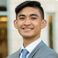 A person in a grey suit and blue tie.