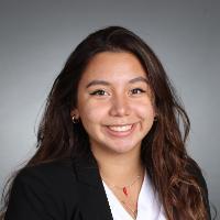 A woman in a black blazer smiles in a headshot photo.