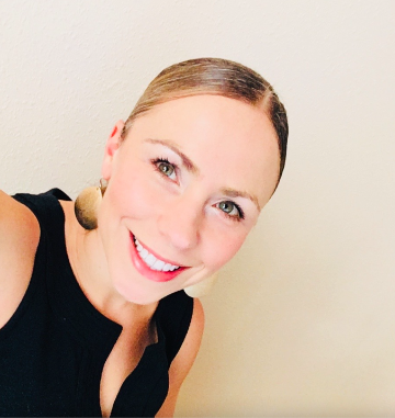 A woman smiling against a plain background.