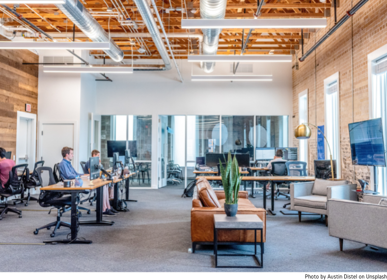 Photo of open coworking space with desks, meeting room, and people.