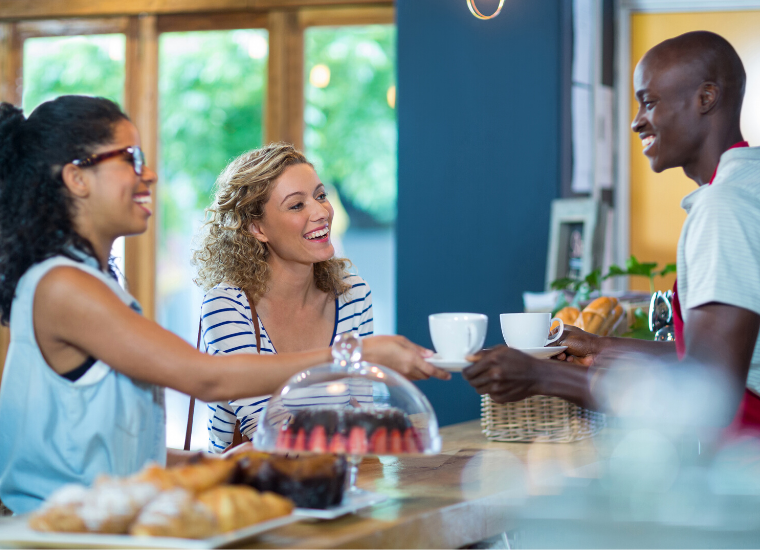 A barista talking and serving two customers. 