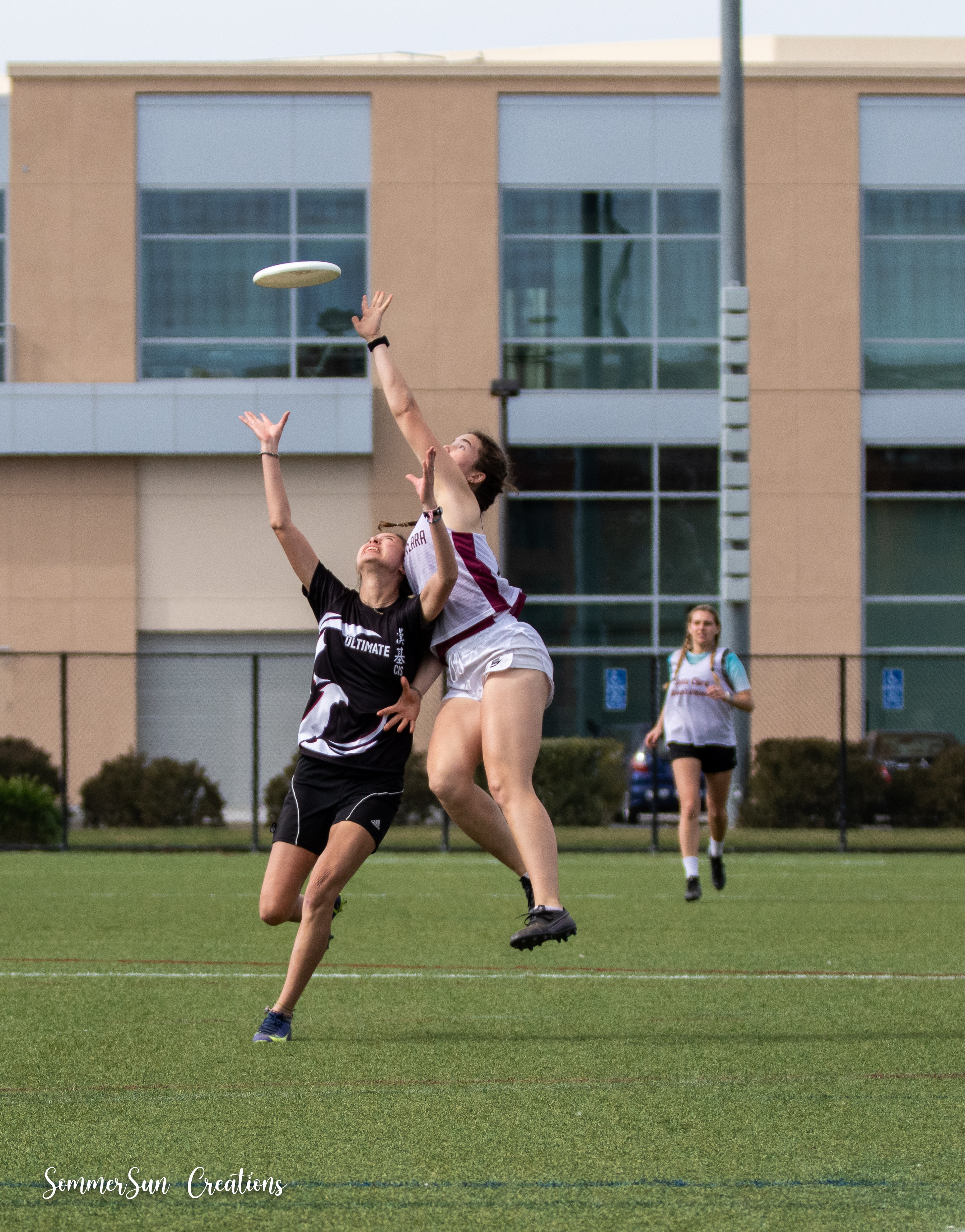 Two Ultimate Frisbee players jump to catch the disc during a game.