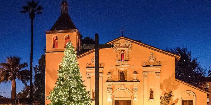 An image of the mission church with a Christmas tree in front of it