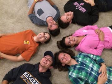 Six people laying on the ground in a circular formation.