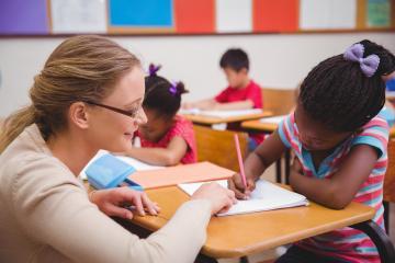 A teacher assisting a student in a classroom setting.