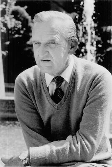 Black and white portrait of John B. Drahmann in a sweater and tie.
