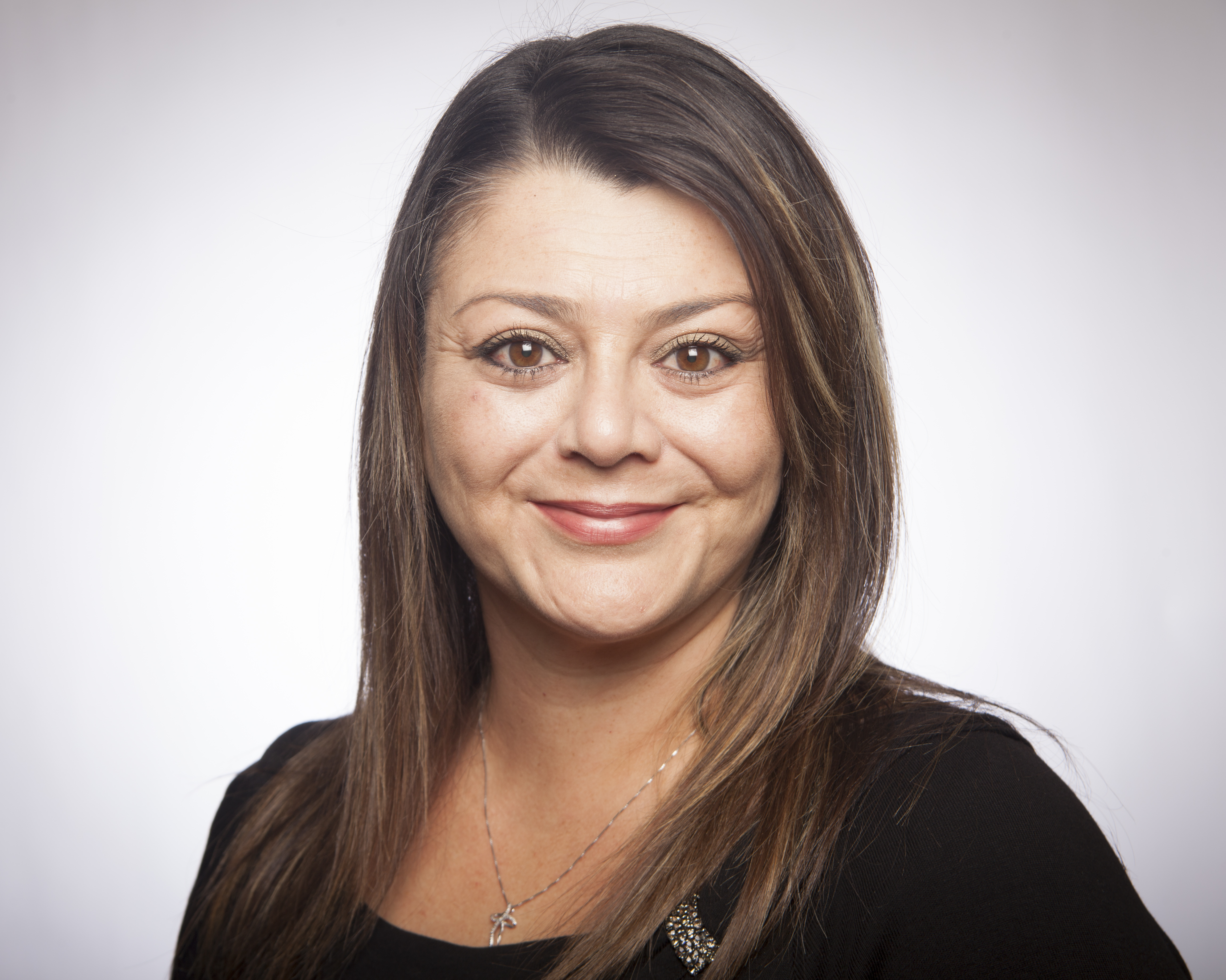 A woman smiling with a neutral background.