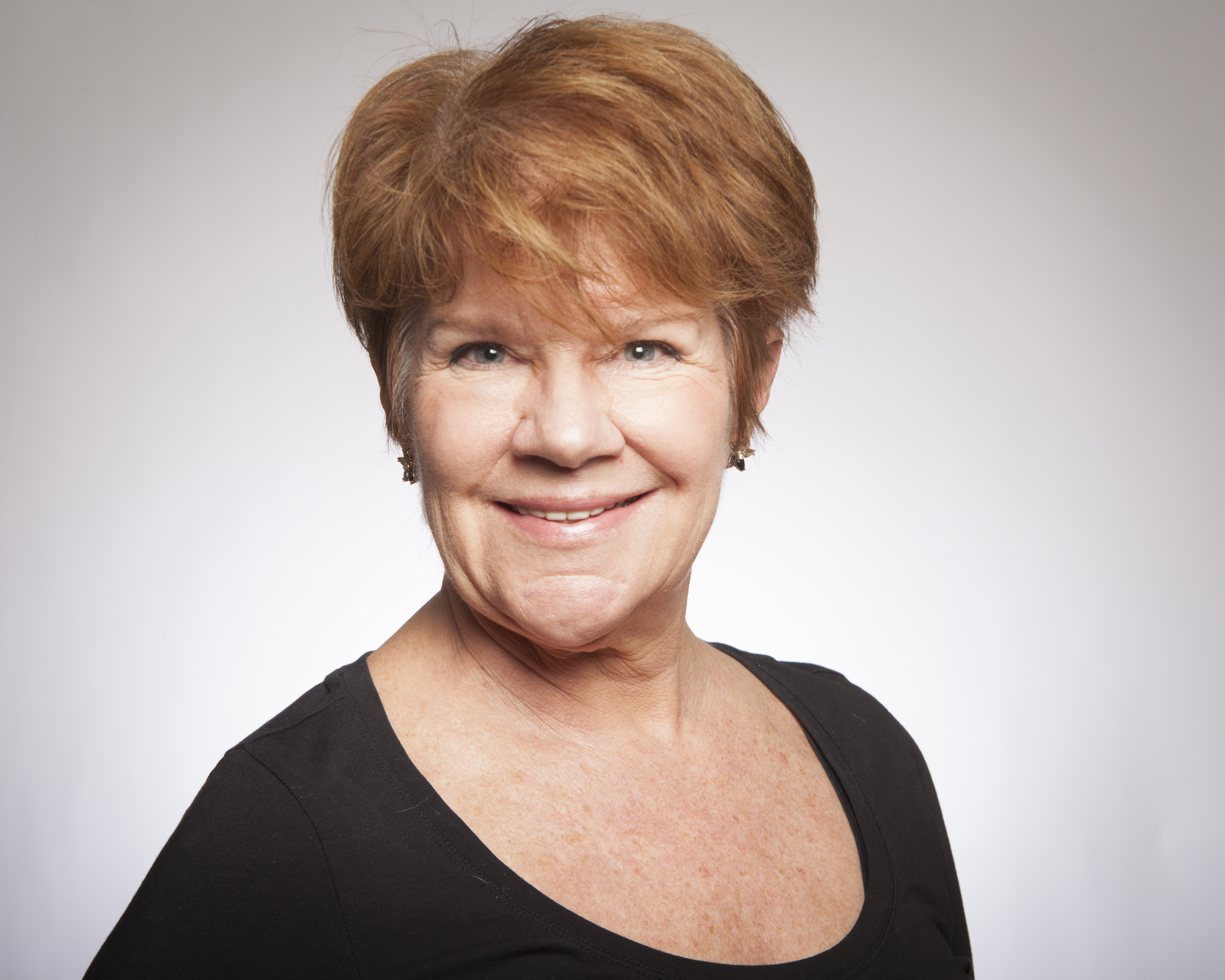 A woman smiling against a plain background.