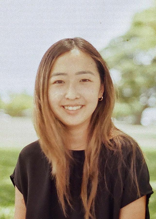 A person wearing a black shirt, smiling outdoors.