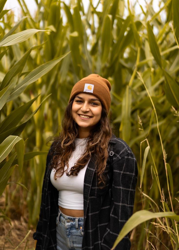 A person smiling in a field of tall green plants.