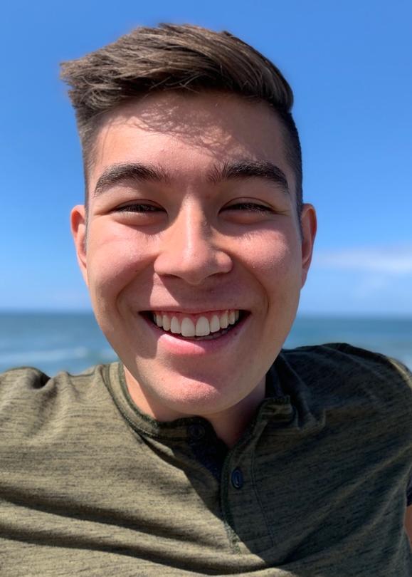 A person smiling with the ocean in the background.