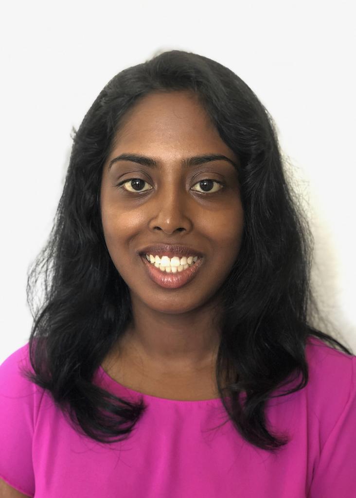 A person in a bright pink top smiling at the camera.