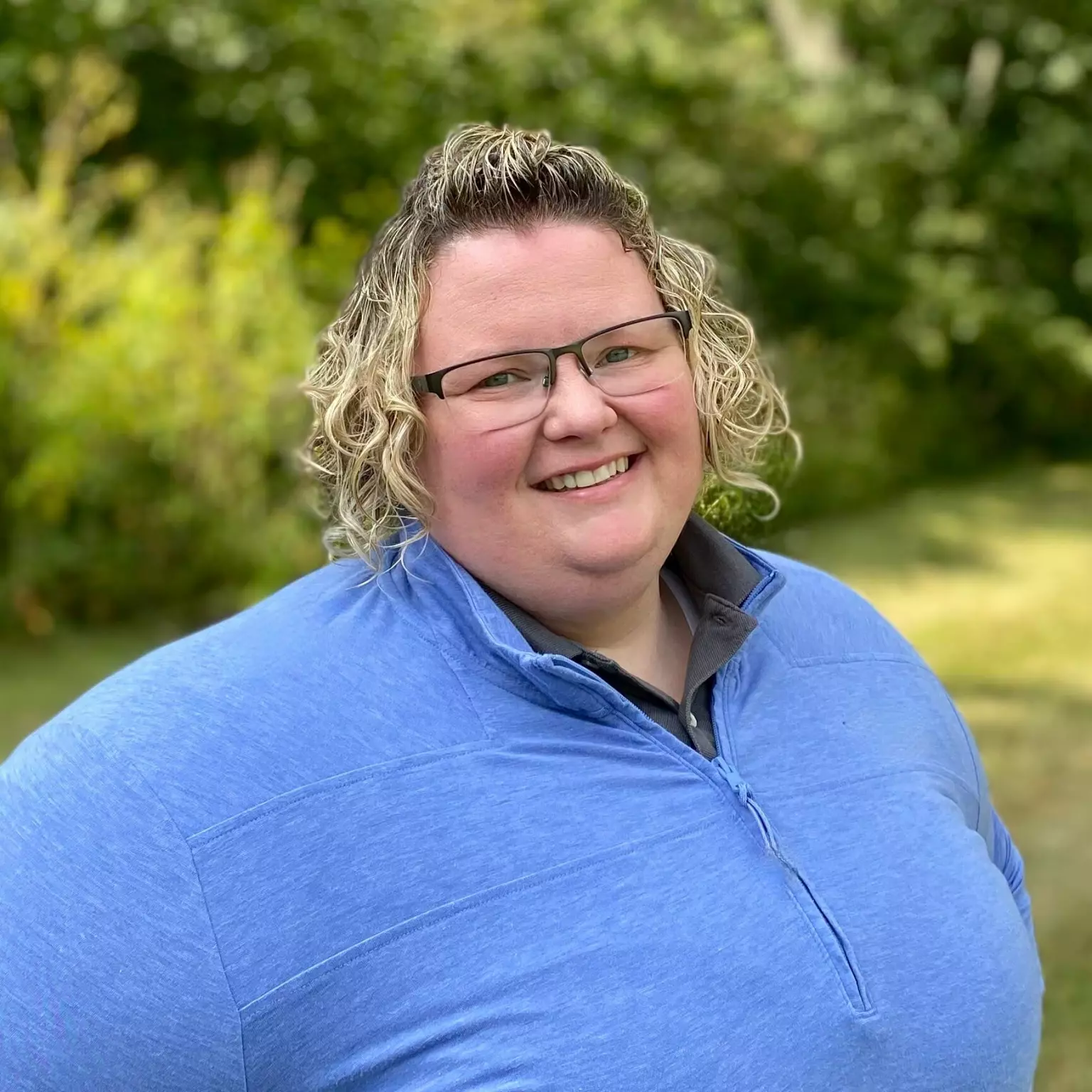 Deputy Director Jessica Ward is wearing a blue quarter zip pullover and has glasses.