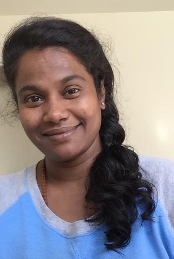 A person smiling with a light blue and white shirt.