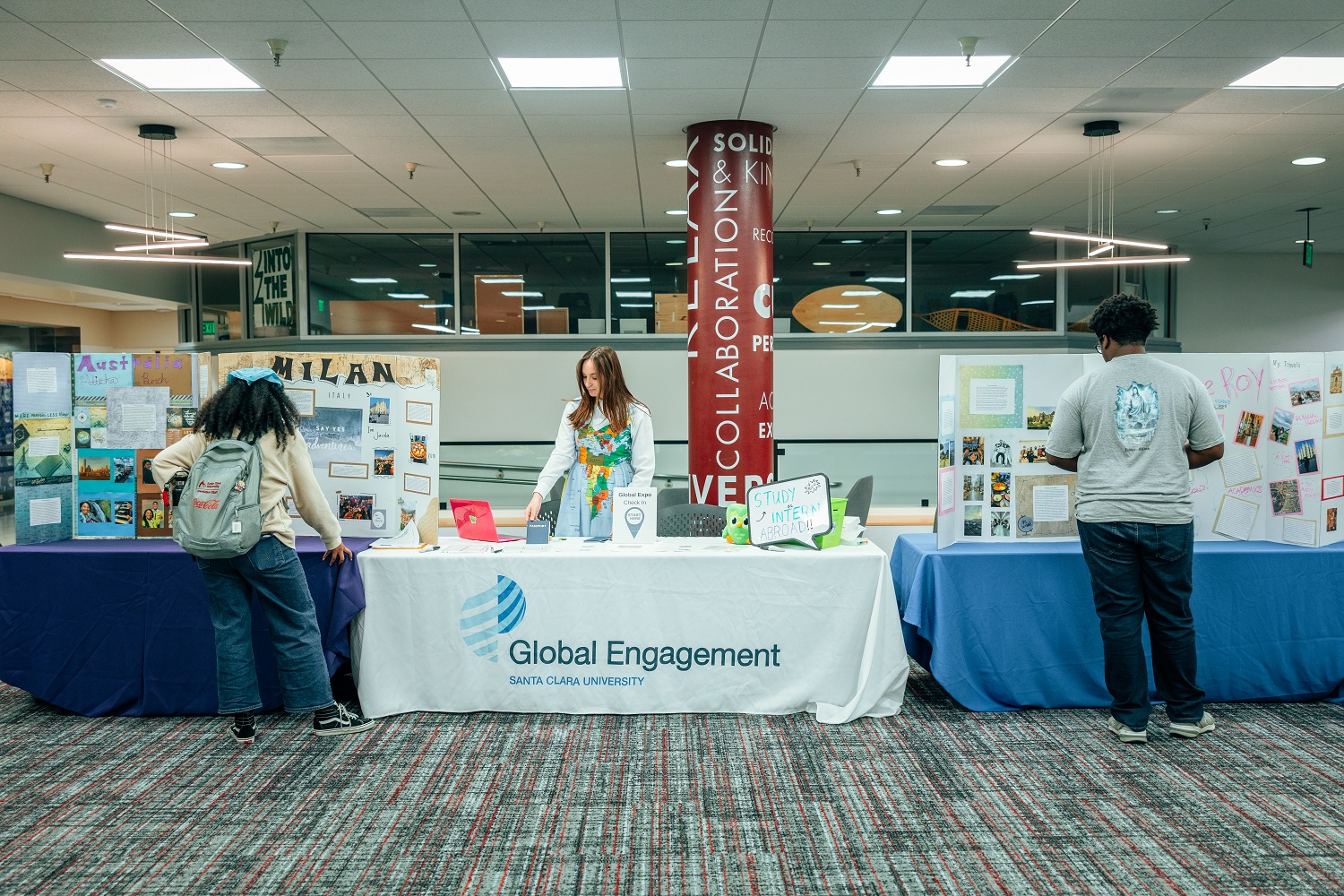 Decorative; Global Engagement staff at branded table speaking to students