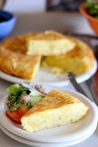 Alt text: Sliced tortilla de patatas served on a plate with vegetables.