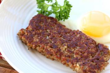 Pan-fried Goetta with a parsley garnish and a side of eggs.
