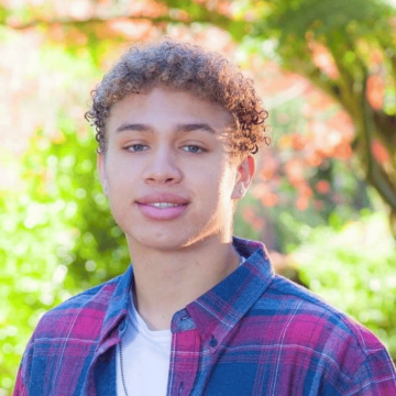 A person wearing a plaid shirt stands outdoors.