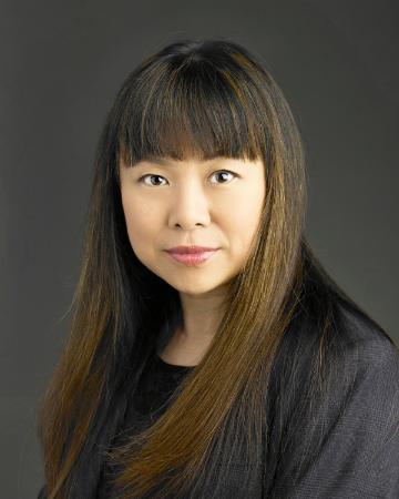 A person posing for a professional photograph against a dark background.