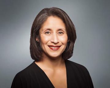 A woman smiling in a professional headshot with a grey background.