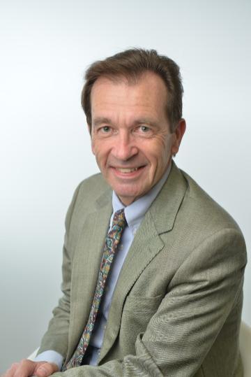 A person smiling and wearing a suit and tie.