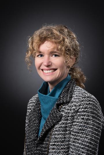 A person smiling against a dark background.