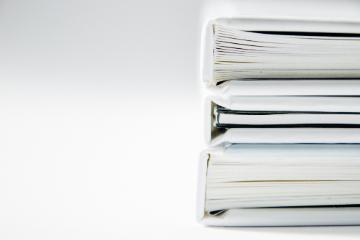 Stack of white and silver binders against a light background.