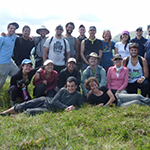 A group of people posing outdoors on a grassy hill.