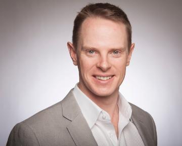 A man in a light-coloured blazer smiling at the camera.