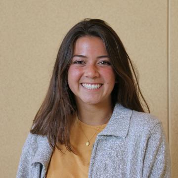 A person smiling in front of a plain background.