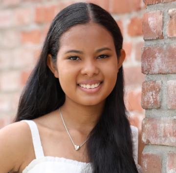 Person smiling in front of a brick wall.