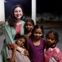 A woman posing with four girls outdoors at night.