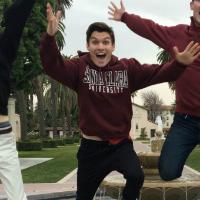 Three people jumping outside with smiles.