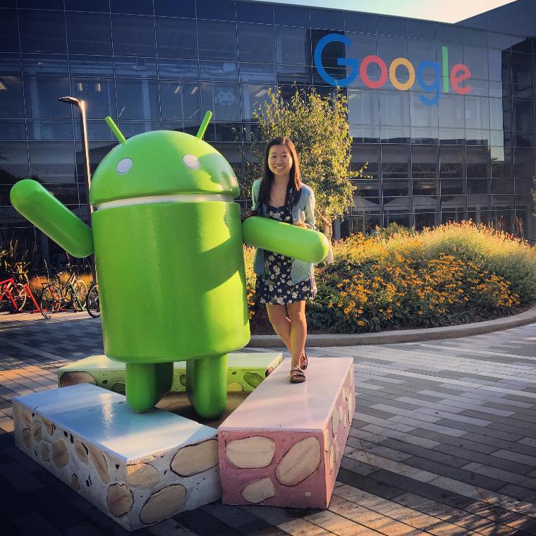 Person posing with Android statue at Google's campus.