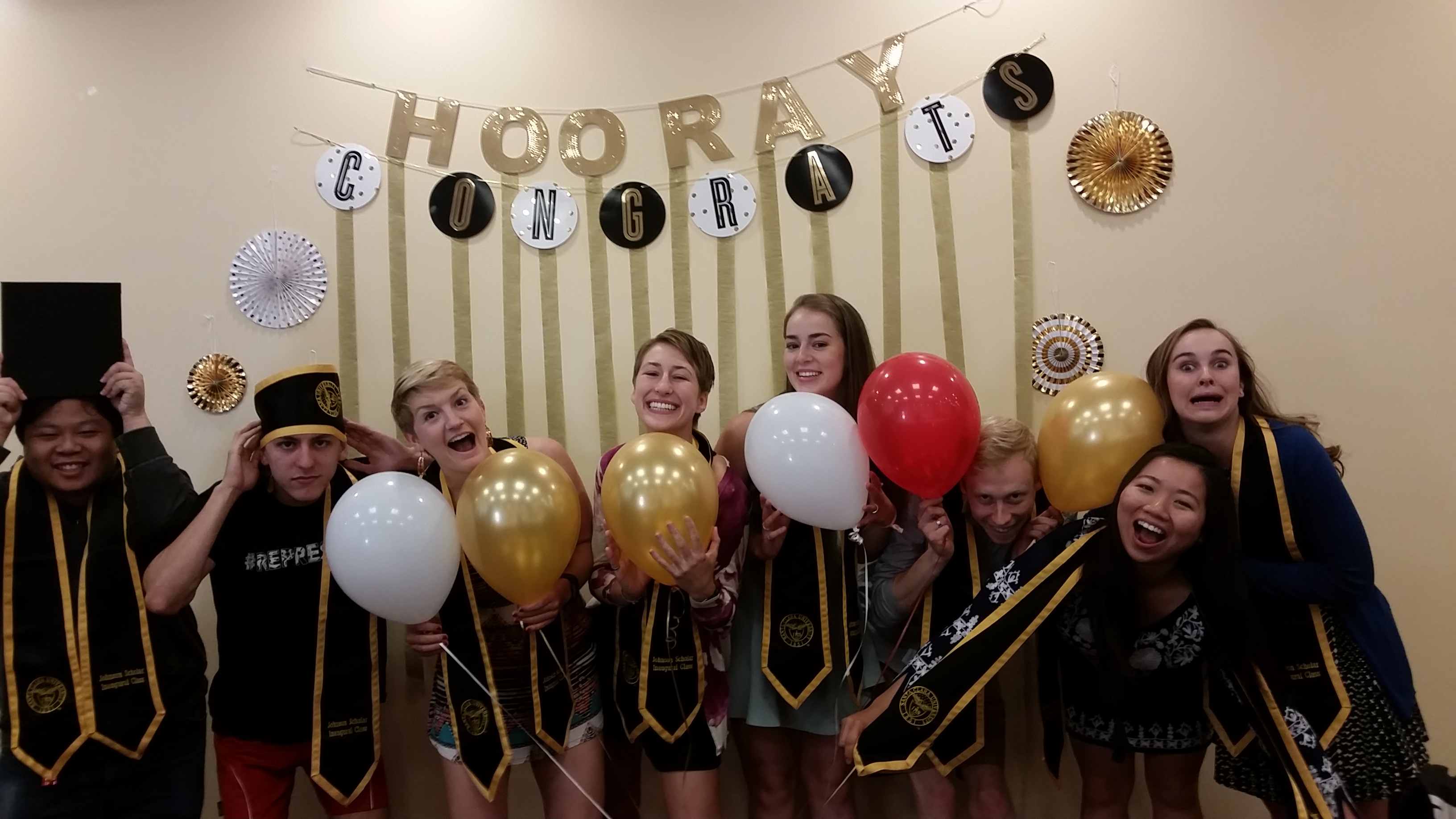 A group photo of graduates at a brunch with balloons.