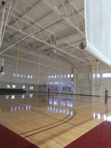 Indoor basketball court with lights on in one section.
