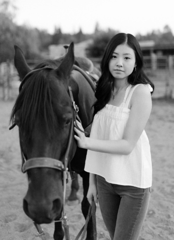 A woman standing next to a horse.