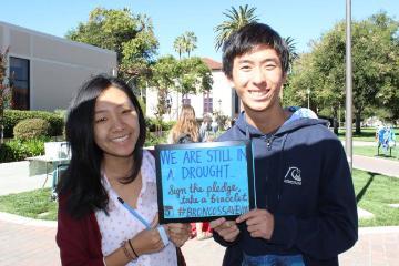 Two people holding a sign reading 