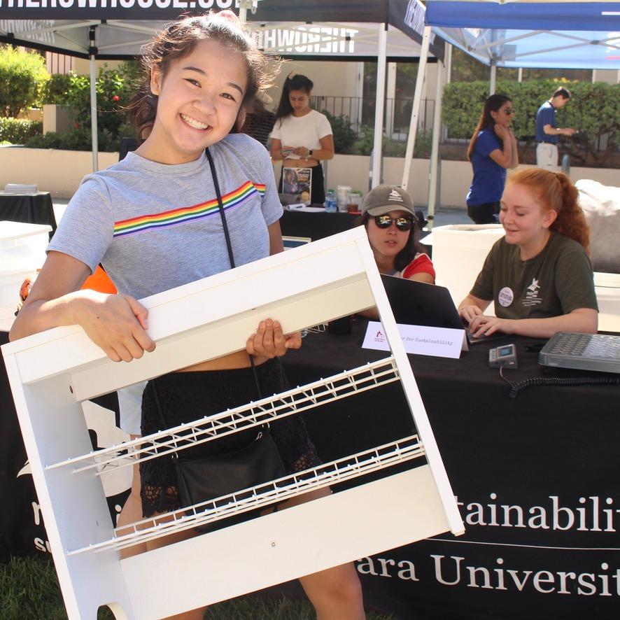 student smiling and holding a shelf