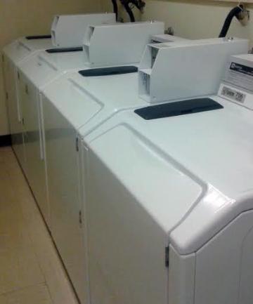 A row of white top-load washing machines in a laundry room.