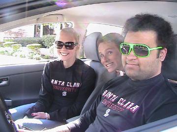 Three people wearing sunglasses sit inside a car.