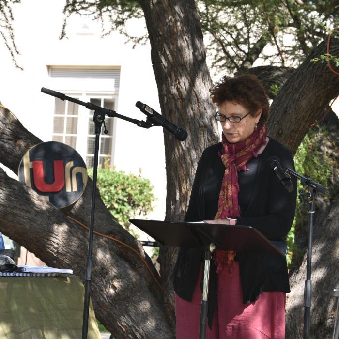 A professor reading Laudato Si next to the tUrn sign under a tree. Photo by Gabby Yabut.