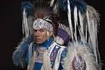 Person in traditional Native American regalia with blue, white, and purple details.