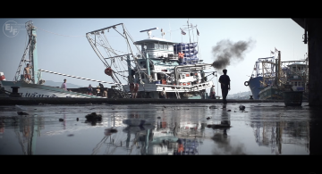 A docked boat emits exhaust with the silhouette of a man walking next to it