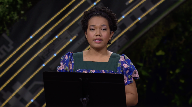 Youth climate warrior Selina Leem speaks at a podium with strings of yellow lights behind her