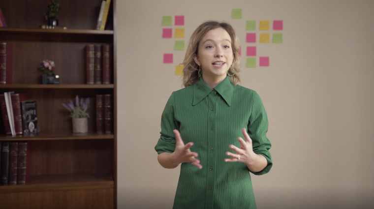 Youth activist Clover Hogan speaks with a bookshelf and wall of Post-It notes in the background